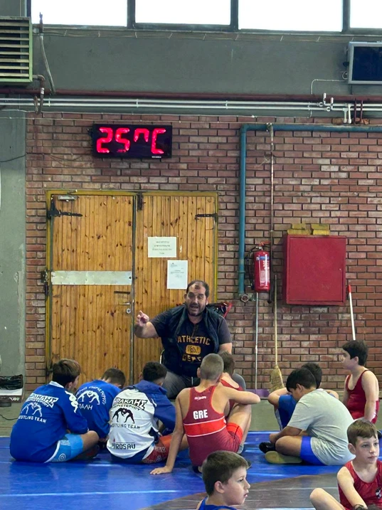 The coach talking to the club's young wrestlers on the mat